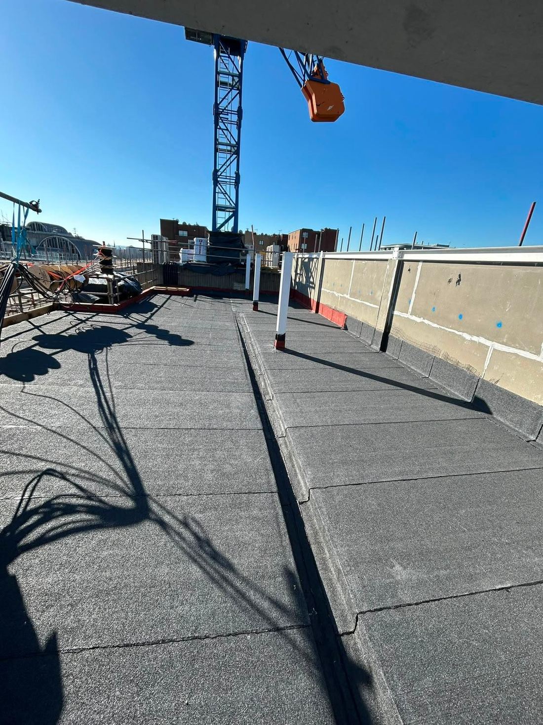 Commercial roofing works alongside a tower crane