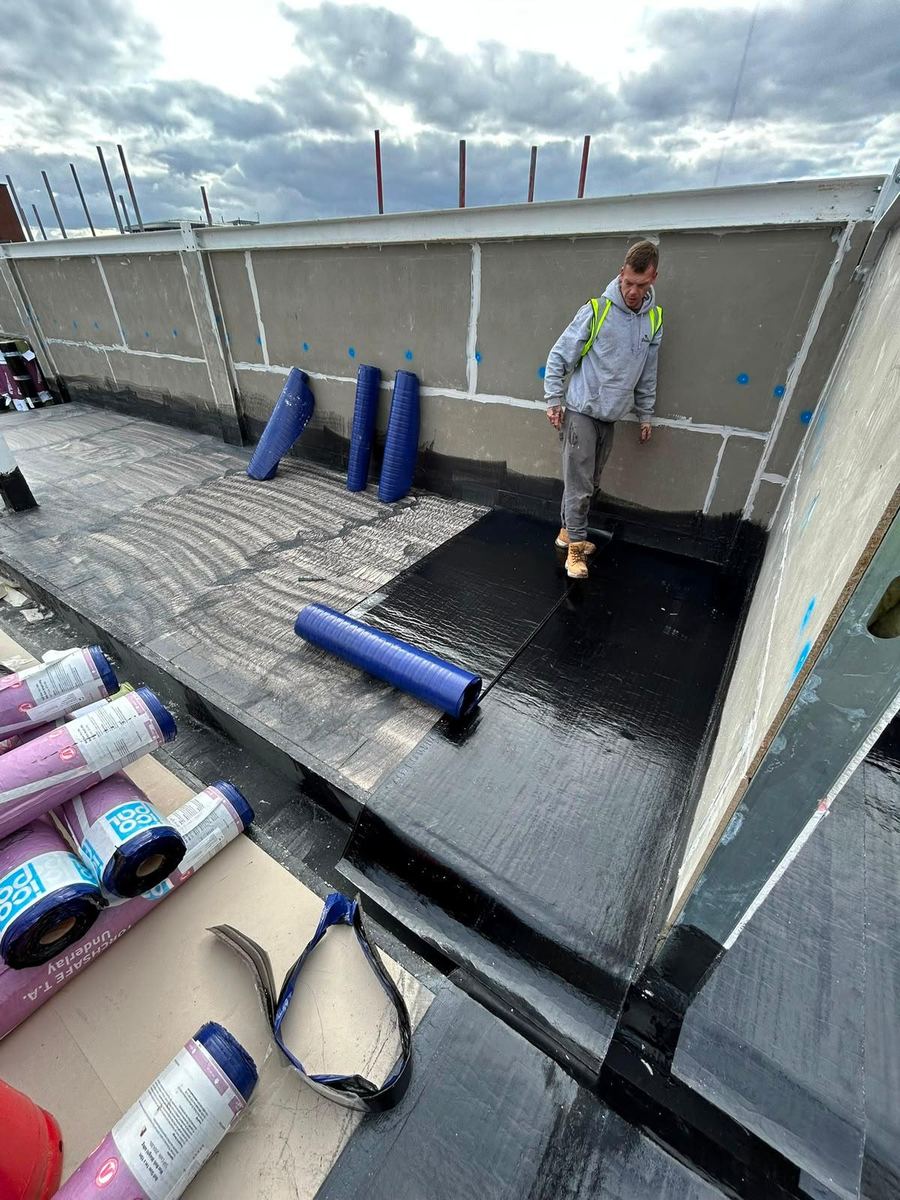 Rolls of membrane being laid on a commercial roof