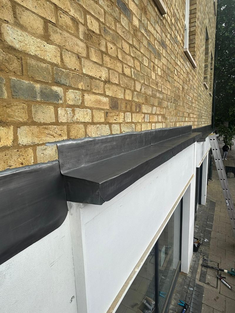 Lead apron flashing dressed along a brick wall